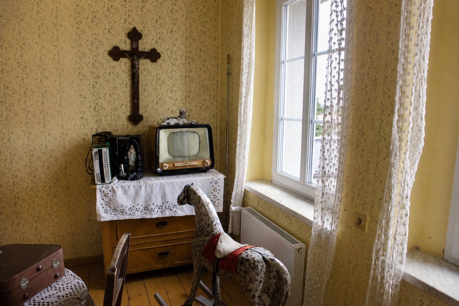 Wnętrze mieszkania z zabytkowym telewizorem, koronkami i koniem na biegunach