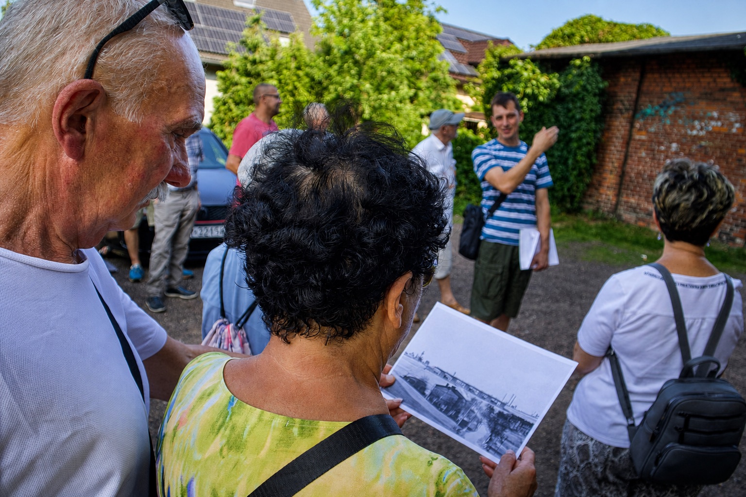 Mieszkańcy oglądają archiwalną fotografię podczas spaceru pamięci